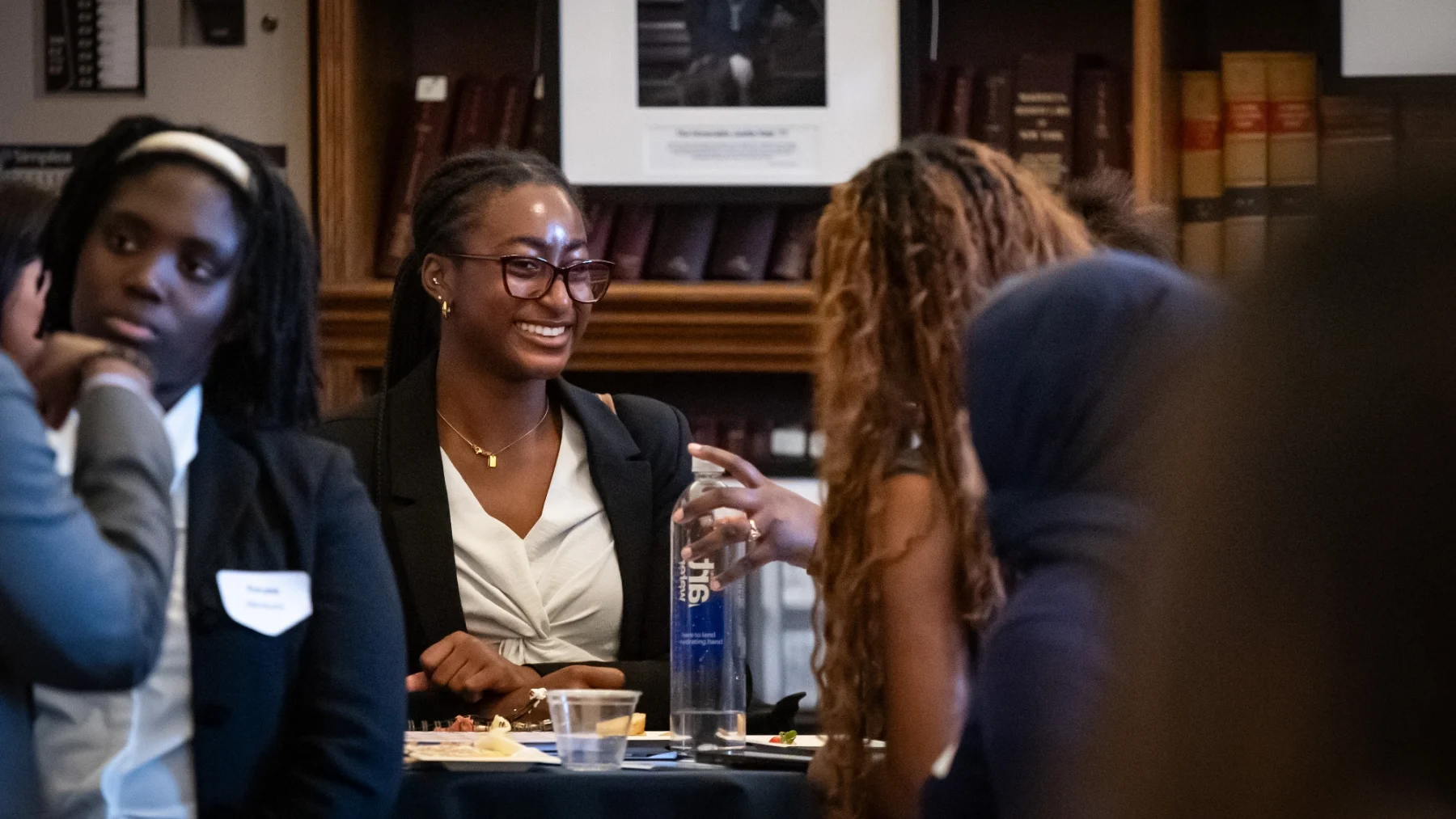 Female student of color smiling with other students.